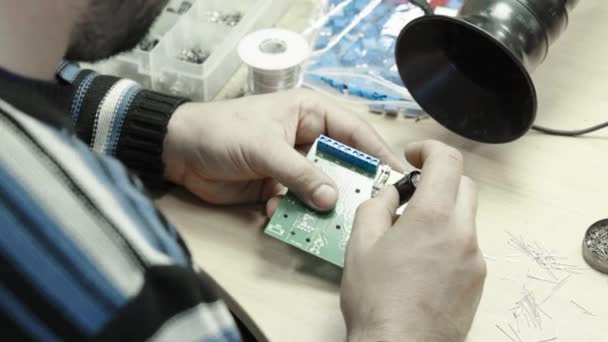 Een werknemer werkt aan de oprichting van een elektronisch bord. Close-up. — Stockvideo