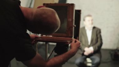 Bir fotoğrafçı, stüdyoda eski bir kamerayla fotoğraf çekiyor..
