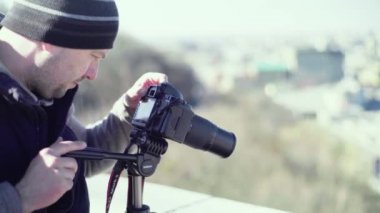 Kameraman fotoğrafçı, elinde kamera DSR 'ıyla şehirde bir tripoda video çekiyor. Kyiv. Ukrayna