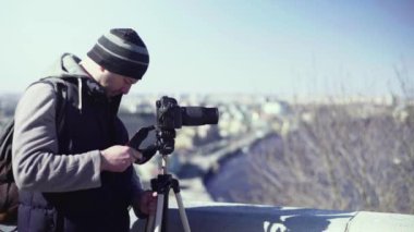 Kameraman fotoğrafçı, elinde kamera DSR 'ıyla şehirde bir tripoda video çekiyor. Kyiv. Ukrayna