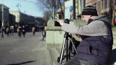 Kameraman fotoğrafçı, elinde kamera DSR 'ıyla şehirde bir tripoda video çekiyor. Kyiv. Ukrayna