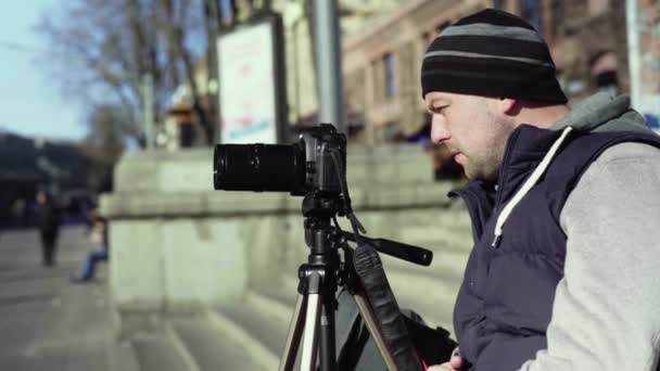 Fotógrafo de câmera com uma câmera DSLR em um tripé na cidade fotografa vídeo. Kiev. Ucrânia — Vídeo de Stock