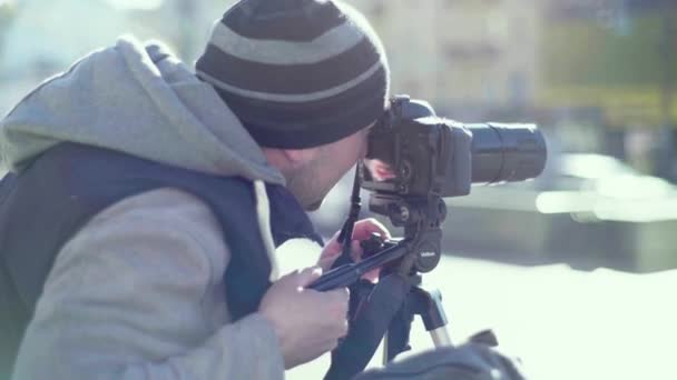 Fotografo cameraman con una fotocamera DSLR su un treppiede in città scatta foto video. Kiev. Ucraina — Video Stock