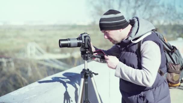 Fotografo cameraman con una fotocamera DSLR su un treppiede in città scatta foto video. Kiev. Ucraina — Video Stock