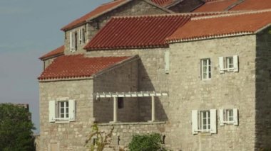 Kırmızı kiremitli çatıları olan evler. Sveti Stefan 'ın mimarisi. Karadağ.