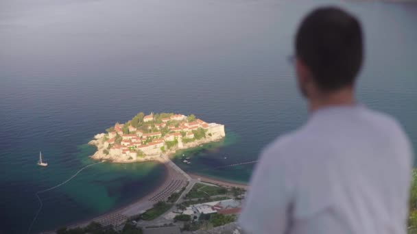 El hombre mira hacia el mar. Sveti Stefan. Montenegro . — Vídeos de Stock