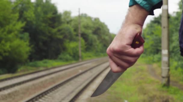 Maniaco con un cuchillo cerca de las vías del tren . — Vídeo de stock