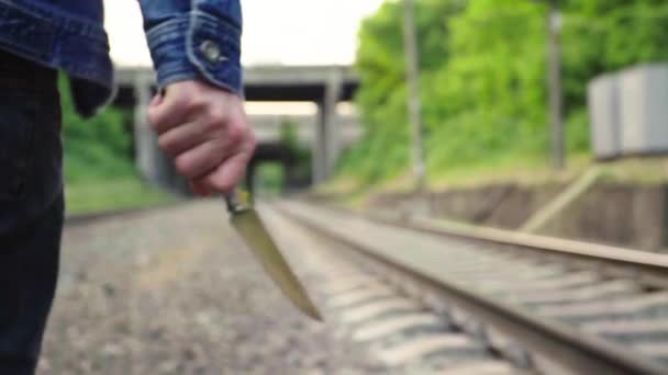 Maniaco con un cuchillo cerca de las vías del tren . — Vídeos de Stock