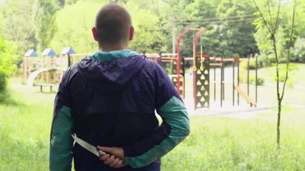 Maníaco com uma faca perto do parque infantil — Vídeo de Stock