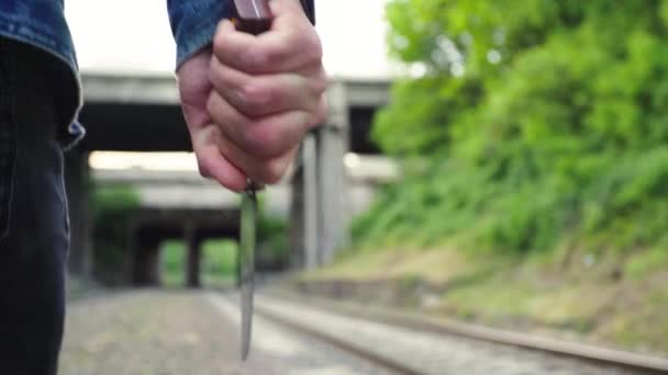 Maniaco con un cuchillo cerca de las vías del tren . — Vídeo de stock