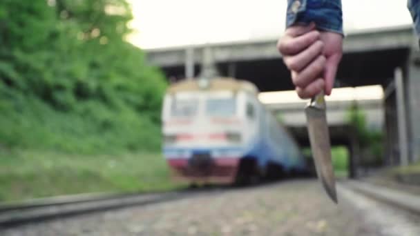 Maniaco con un cuchillo cerca de las vías del tren . — Vídeos de Stock