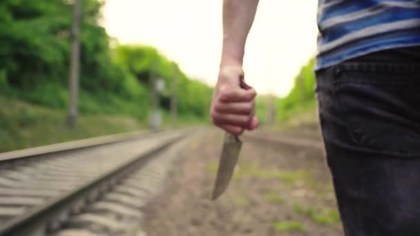 Maniaco con un cuchillo cerca de las vías del tren . — Vídeo de stock