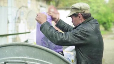 Dilenci evsiz bir serseri çöp tenekesinde yiyecek arıyor. Kyiv. Ukrayna
