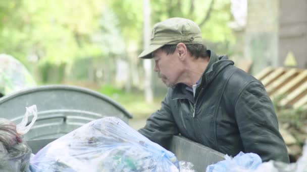 Un vagabundo mendigo sin hogar está buscando comida en un cubo de basura. Kiev. Ucrania — Vídeos de Stock