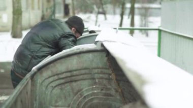 Dilenci evsiz bir serseri çöp tenekesinde yiyecek arıyor. Kyiv. Ukrayna