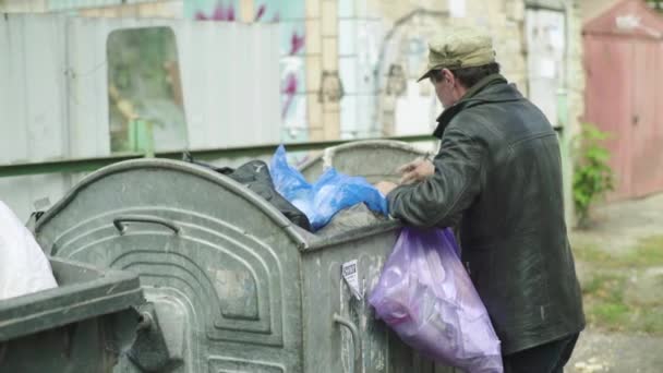 Bezdomny żebrak szuka jedzenia w koszu na śmieci. Kijów. Ukraina — Wideo stockowe