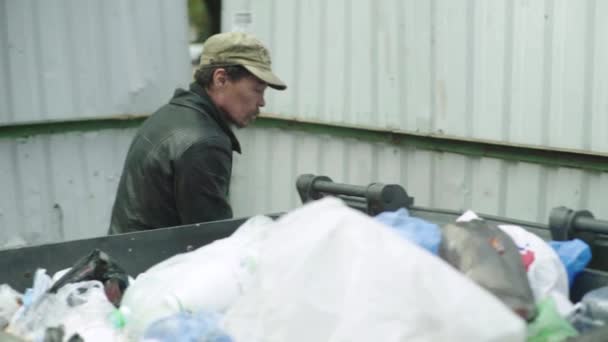 Un vagabundo mendigo sin hogar está buscando comida en un cubo de basura. Kiev. Ucrania — Vídeos de Stock