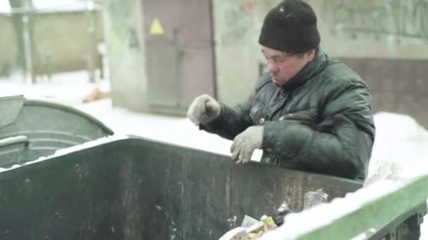 Um mendigo vagabundo anda à procura de comida num caixote do lixo. Kiev. Ucrânia — Vídeo de Stock