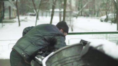 Dilenci evsiz bir serseri çöp tenekesinde yiyecek arıyor. Kyiv. Ukrayna