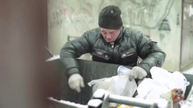Dilenci evsiz bir serseri çöp tenekesinde yiyecek arıyor. Kyiv. Ukrayna