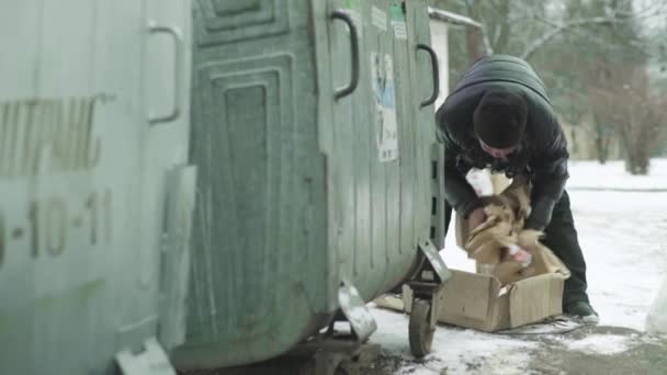 Un vagabundo mendigo sin hogar está buscando comida en un cubo de basura. Kiev. Ucrania — Vídeos de Stock