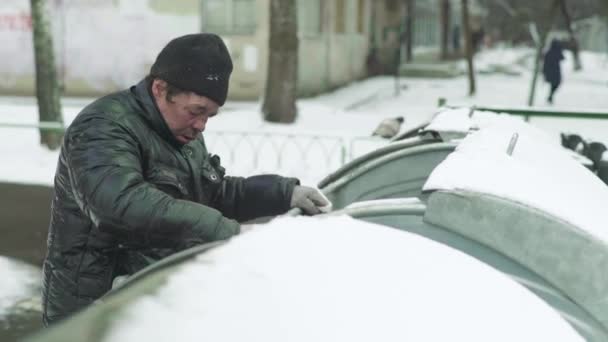 Un vagabundo mendigo sin hogar está buscando comida en un cubo de basura. Kiev. Ucrania — Vídeos de Stock