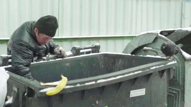 乞食のホームレスの男の罠は、ゴミ箱で食料を探していることができます。キエフ。ウクライナ — ストック動画