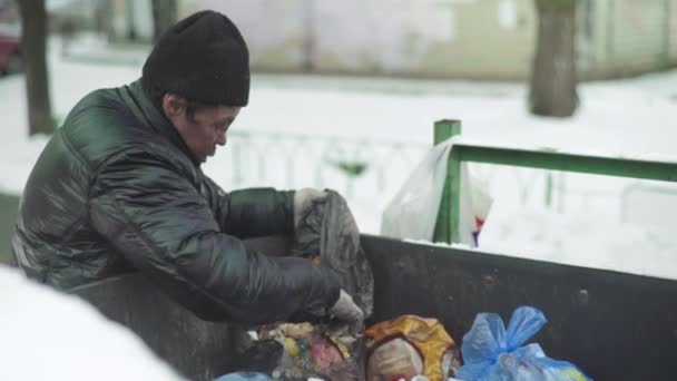 Bezdomny żebrak szuka jedzenia w koszu na śmieci. Kijów. Ukraina — Wideo stockowe