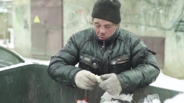 Bezdomny żebrak szuka jedzenia w koszu na śmieci. Kijów. Ukraina — Wideo stockowe