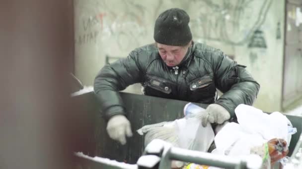 A beggar homeless man tramp is looking for food in a trash can. Kyiv. Ukraine — Stock Video