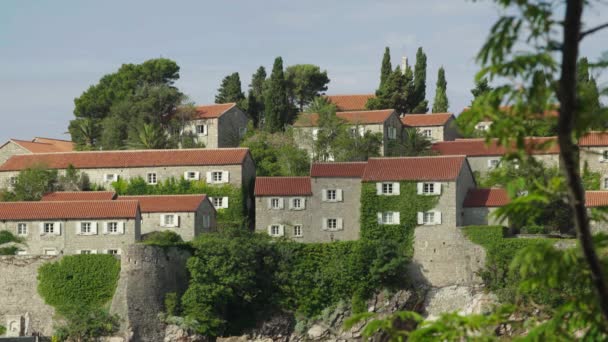 Casas con tejados de tejas rojas. Arquitectura de Sveti Stefan. Montenegro . — Vídeos de Stock