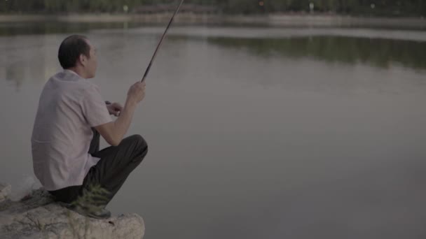 A halász halat fog a tóban. Peking. Kína. Ázsia — Stock videók