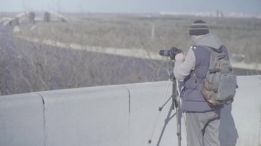 Şehirdeki tripodun üzerinde kamera DSR 'ı olan erkek kameraman fotoğrafçı video çekiyor. Kyiv. Ukrayna