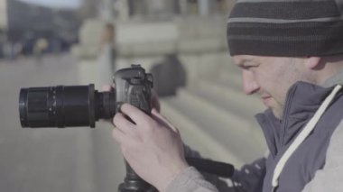 Şehirdeki tripodun üzerinde kamera DSR 'ı olan erkek kameraman fotoğrafçı video çekiyor. Kyiv. Ukrayna