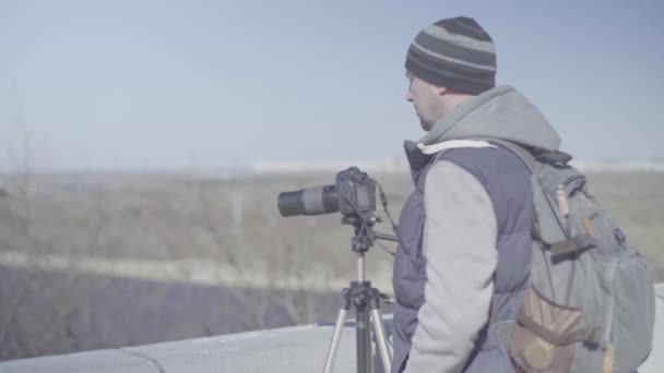 Мужчина фотограф-оператор с камерой DSLR на штативе в городе снимает видео фото. Киев. Украина — стоковое видео