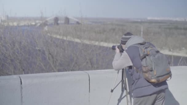 Uomo fotografo cameraman maschile con una fotocamera DSLR su un treppiede in città scatta foto video. Kiev. Ucraina — Video Stock