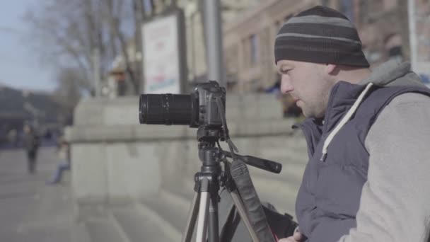 Man male cameraman photographer with a camera DSLR on a tripod in the city shoots video photo . Kyiv. Ukraine — Stock Video