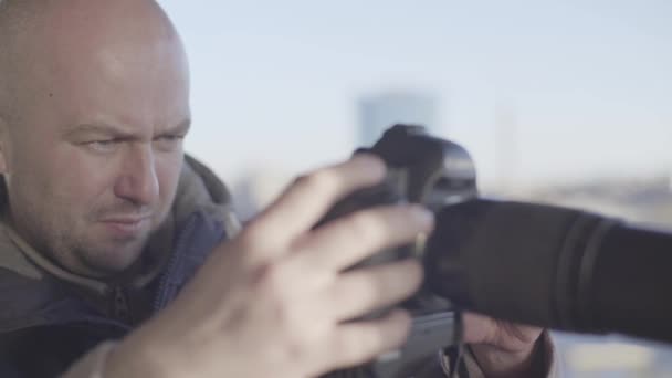 Hombre hombre camarógrafo fotógrafo con una cámara réflex digital en un trípode en la ciudad dispara foto de vídeo. Kiev. Ucrania — Vídeos de Stock