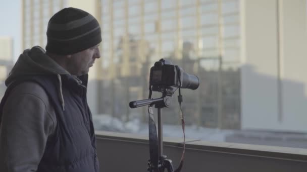 Homem fotógrafo cameraman masculino com uma câmera DSLR em um tripé na cidade fotografa vídeo. Kiev. Ucrânia — Vídeo de Stock