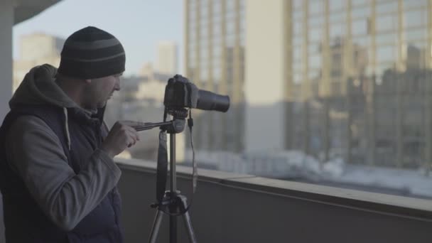 Mężczyzna kamerzysta fotograf z aparatem fotograficznym Dslr na statywie w mieście robi zdjęcia wideo. Kijów. Ukraina — Wideo stockowe