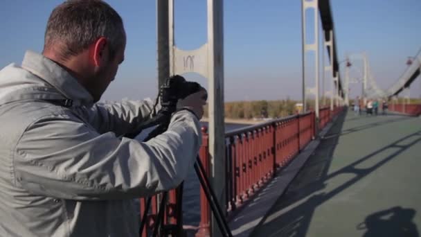 Ein männlicher Kameramann fotografiert mit einer Kamera auf einem Stativ in der Stadt Videoaufnahmen. kyiv. Ukraine — Stockvideo
