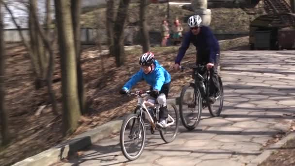 Far och son cyklar i parken. Faderskap. Lycklig barndom. Sakta i backarna. Kiev. Ukraina. — Stockvideo