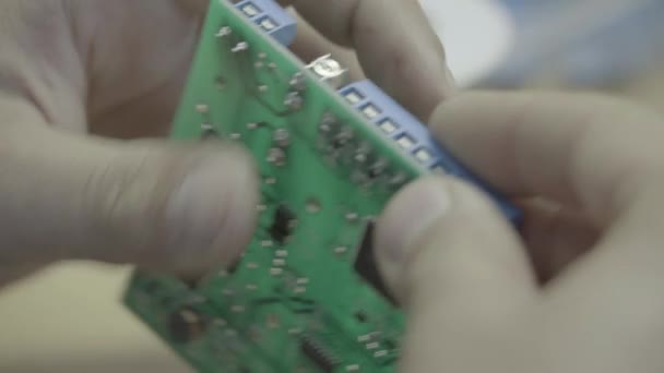 Een werknemer werkt aan de productie van een elektronisch bord. Close-up. — Stockvideo