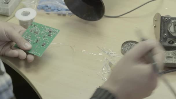 Een werknemer werkt aan de productie van een elektronisch bord. Close-up. — Stockvideo