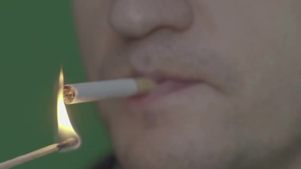 Un cigarrillo en la boca de un fumador. Primer plano. En cámara lenta. Chroma Key. Fondo verde . — Vídeo de stock