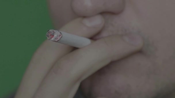 Cigaretta egy dohányos szájában. Közelkép. Lassú mozgás. Krómkulcs. Zöld háttér. — Stock videók