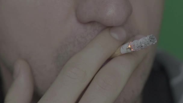 Cigarett i munnen på en rökare. Närbild. Sakta i backarna. Chroma nyckel. Grön bakgrund. — Stockvideo