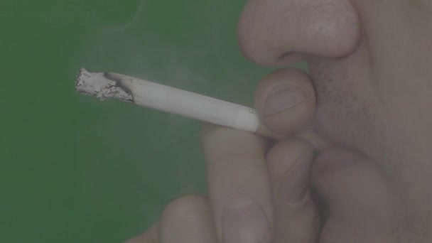 Cigarett i munnen på en rökare. Närbild. Sakta i backarna. Chroma nyckel. Grön bakgrund. — Stockvideo