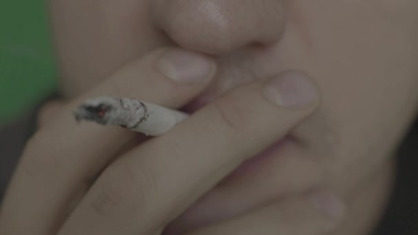Sigaretta in bocca a un fumatore. Primo piano... chiave cromatica. Sfondo verde . — Video Stock