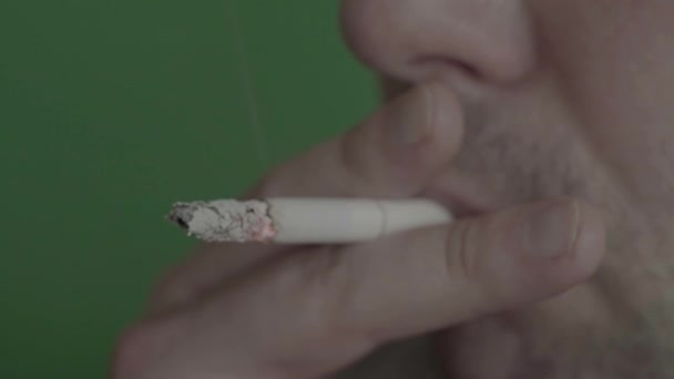 담배를 피우는 사람 의입 속에 담배를 넣는다. 클로즈업, 크로마 키. 녹색 배경. — 비디오